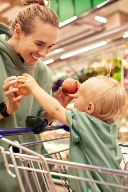 eine Mutter mit Kind im Einkaufswagen in einem Supermarkt