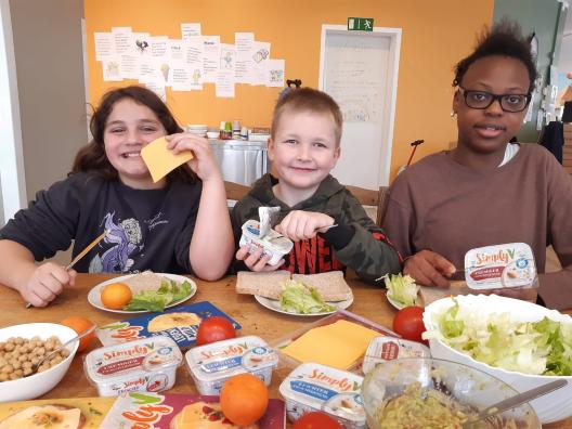 Kinder an einem Frühstückstisch mit gesunden Lebensmitteln