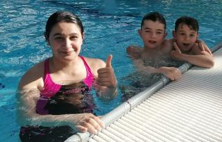 drei Kinder im Wasser lernen schwimmen