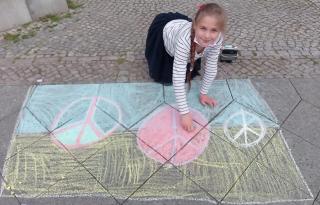ein Mädchen malt mit Kreide auf dem Bürgersteig